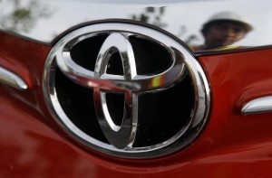 Worker is reflected next to the emblem of a Toyota Vios sedan at a stockyard of the Toyota Philippines manufacturing plant in Sta Rosa, Laguna, south of Manila